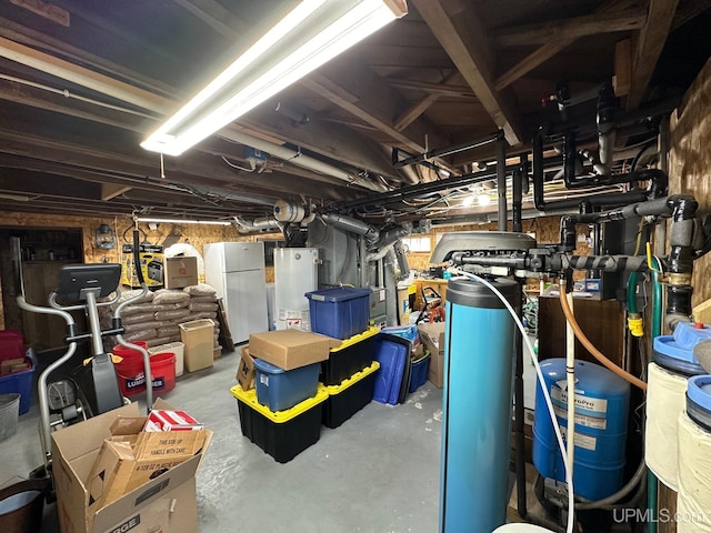 basement with water heater and white refrigerator