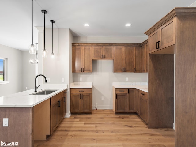 kitchen with coffered ceiling, ceiling fan, sink, decorative light fixtures, and light hardwood / wood-style flooring