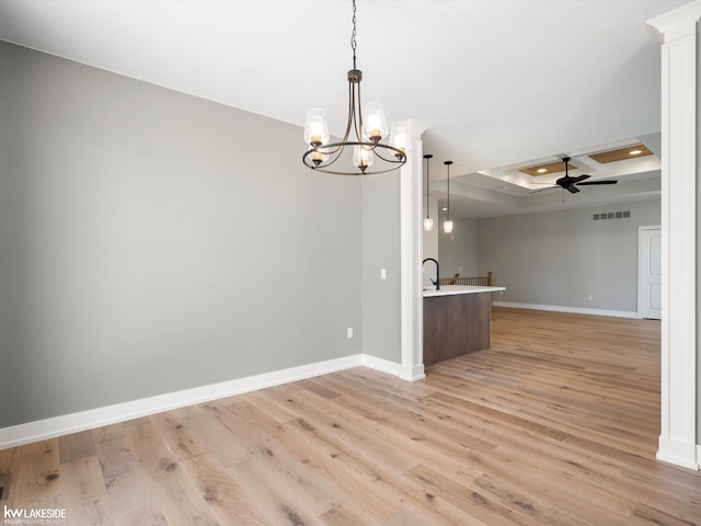 kitchen with sink, light stone counters, kitchen peninsula, decorative light fixtures, and light wood-type flooring