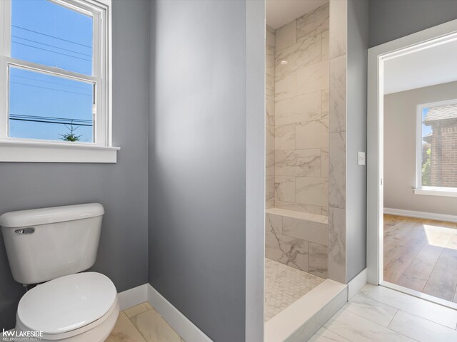 bathroom featuring a tile shower, hardwood / wood-style flooring, and toilet