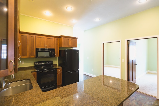 kitchen with dark stone counters, tile flooring, black appliances, and sink