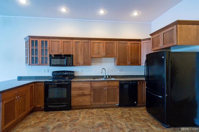 kitchen with dark stone counters, crown molding, sink, and black appliances