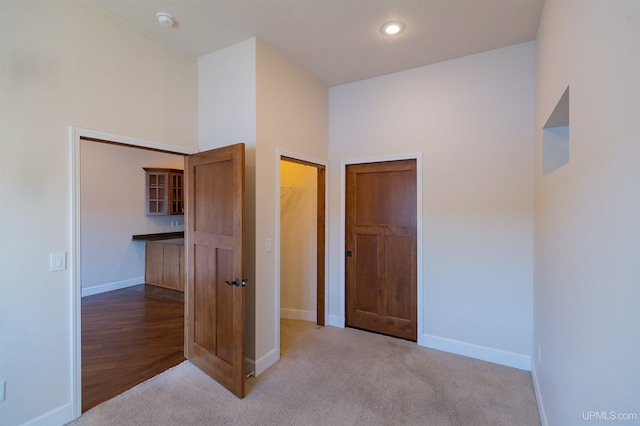 unfurnished bedroom featuring a spacious closet, light colored carpet, and a closet