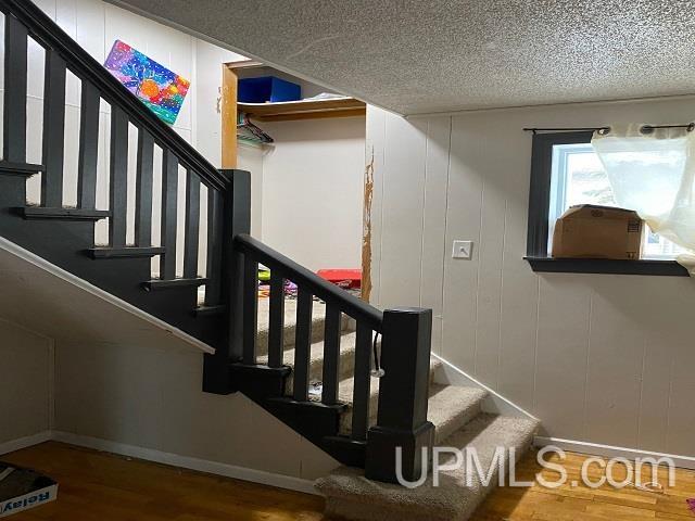 stairway with a textured ceiling and hardwood / wood-style flooring