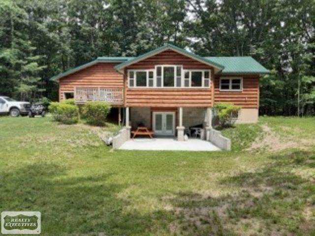 rear view of property with a patio, a wooden deck, and a lawn