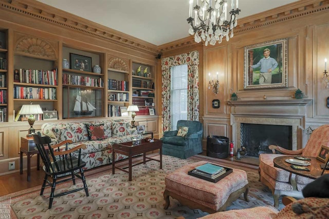 living area featuring ornamental molding, a chandelier, light wood-type flooring, and built in shelves