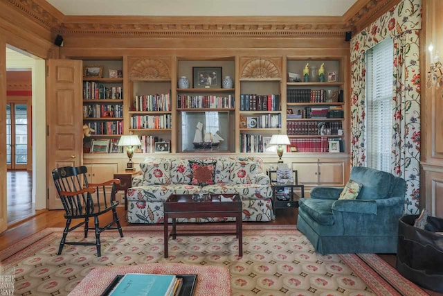 sitting room featuring ornamental molding, light wood-type flooring, and built in features