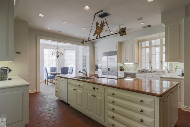 kitchen with sink, a wealth of natural light, built in appliances, and a kitchen island with sink