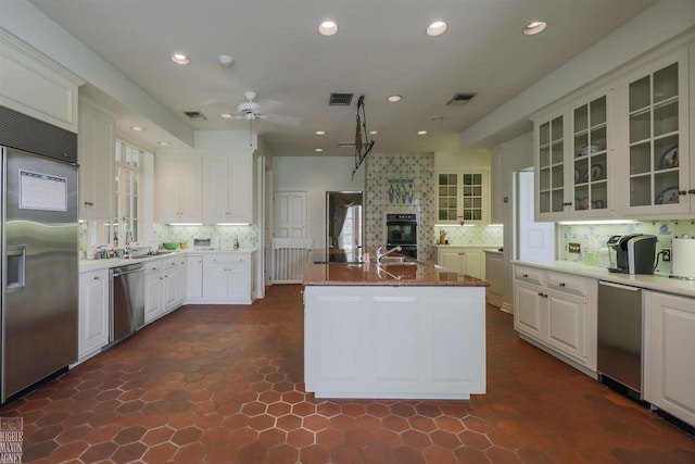 kitchen with dark tile floors, ceiling fan, a large fireplace, and stainless steel appliances