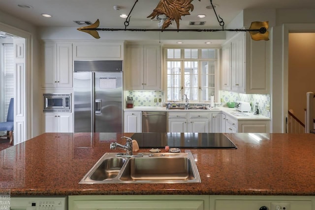 kitchen with white cabinetry, sink, and built in appliances