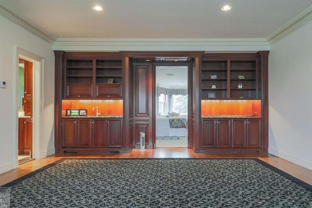 bar featuring backsplash, crown molding, light hardwood / wood-style flooring, and sink