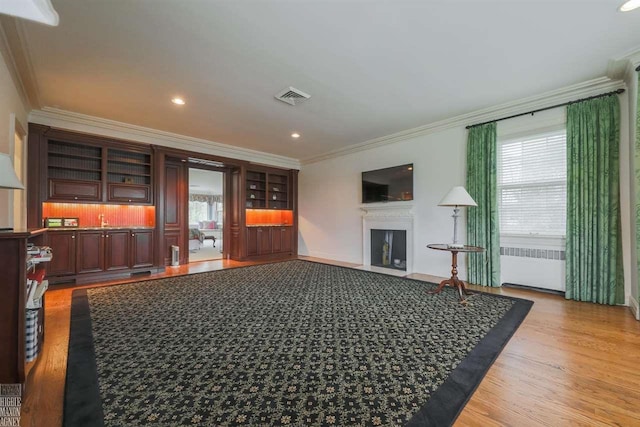 living room with plenty of natural light, light hardwood / wood-style floors, and crown molding