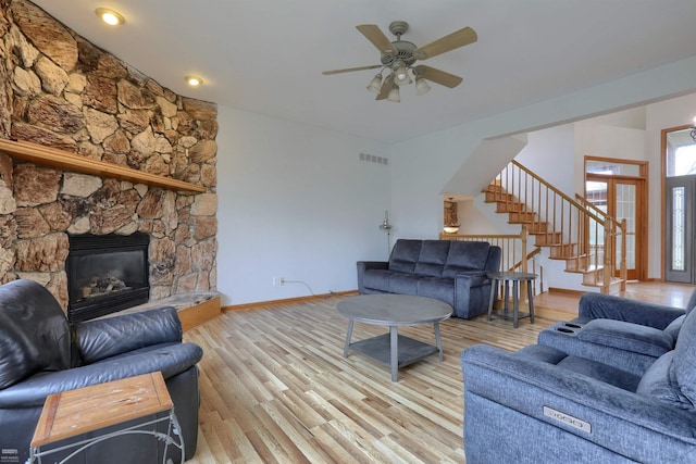 living room with ceiling fan, light wood-type flooring, and a fireplace