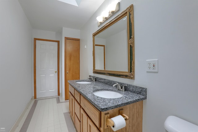 bathroom with tile flooring, toilet, and dual bowl vanity