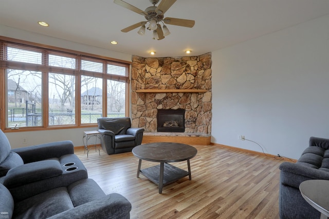 living room with ceiling fan, light wood-type flooring, and a fireplace