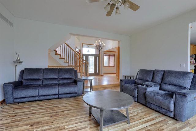 living room with light hardwood / wood-style floors and ceiling fan with notable chandelier