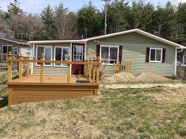 back of property with a wooden deck and a yard