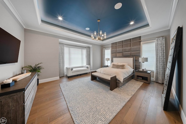 bedroom featuring a notable chandelier, hardwood / wood-style flooring, ornamental molding, and a raised ceiling