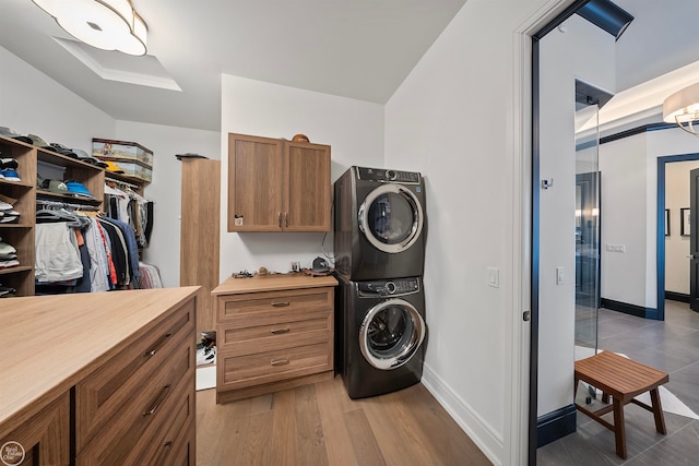 clothes washing area featuring stacked washing maching and dryer and wood-type flooring