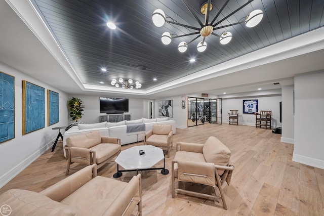 living room with an inviting chandelier, a tray ceiling, and light wood-type flooring