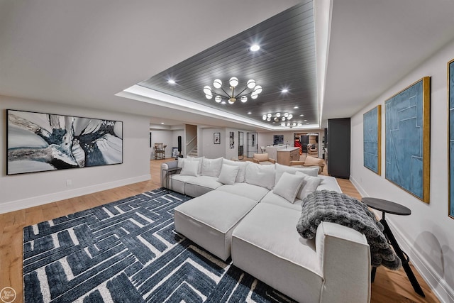 living room featuring a notable chandelier, a raised ceiling, and hardwood / wood-style floors