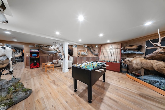 rec room with wooden walls, light hardwood / wood-style floors, and ornate columns