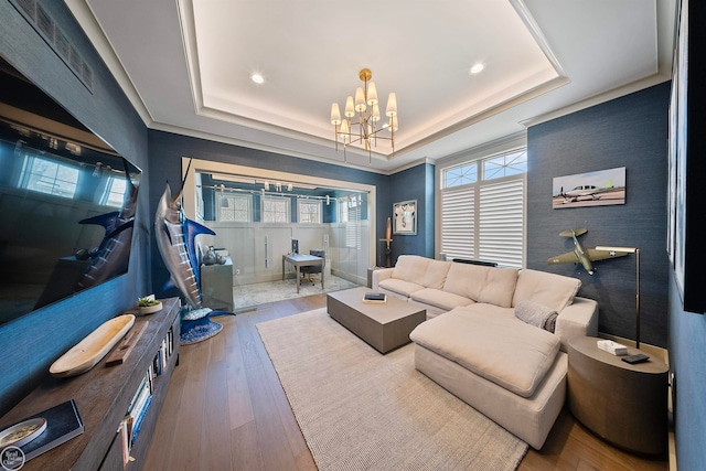 living room featuring a notable chandelier, a raised ceiling, and hardwood / wood-style floors