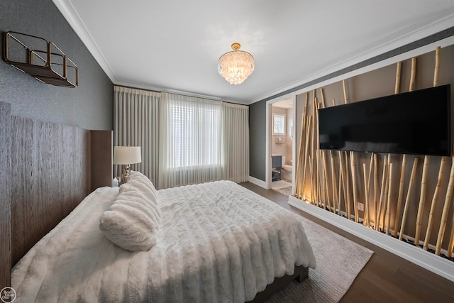 bedroom with crown molding, wood-type flooring, a notable chandelier, and ensuite bath