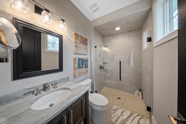 bathroom featuring a shower with door, vanity, and toilet