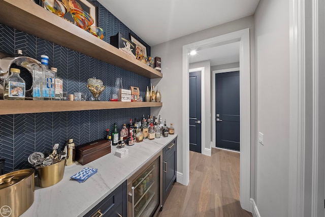 bar with light stone countertops and light hardwood / wood-style flooring