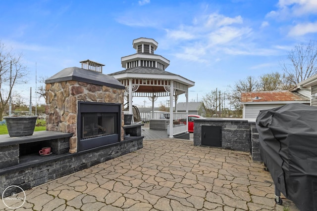 view of patio / terrace with an outdoor stone fireplace and a gazebo