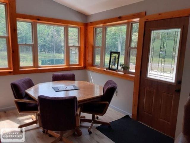 dining room featuring a healthy amount of sunlight, vaulted ceiling, and hardwood / wood-style floors