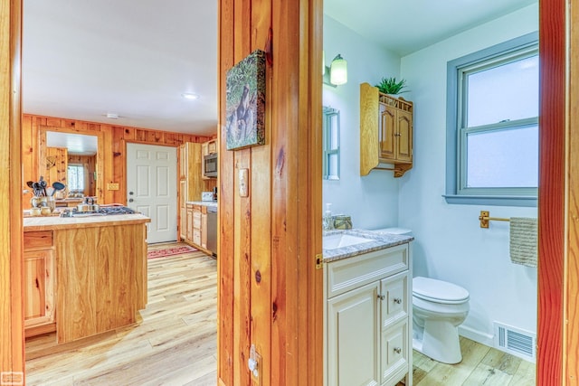 bathroom with vanity, wooden walls, toilet, and hardwood / wood-style flooring