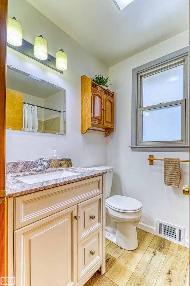 bathroom featuring wood-type flooring, toilet, and vanity