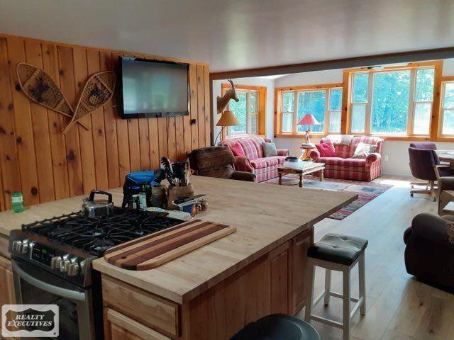 interior space featuring gas range oven, hardwood / wood-style flooring, a breakfast bar, and wooden walls