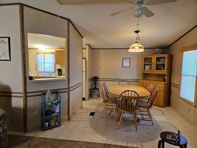 dining area featuring ceiling fan, light carpet, and ornamental molding