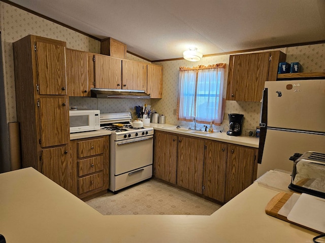 kitchen with white appliances, vaulted ceiling, crown molding, light tile flooring, and sink