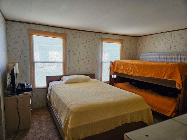 bedroom featuring dark carpet, a textured ceiling, and multiple windows