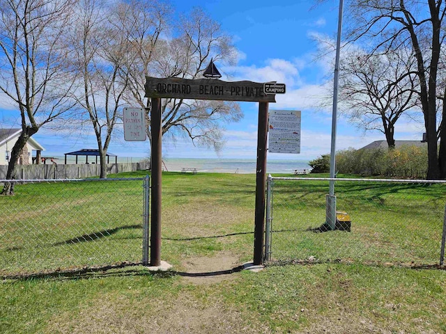 community sign with a water view and a lawn