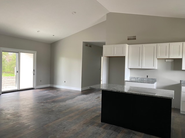 kitchen featuring light stone counters, dark wood-type flooring, high vaulted ceiling, white cabinets, and a center island