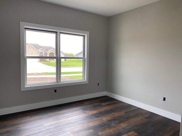 unfurnished room featuring dark wood-type flooring and a wealth of natural light