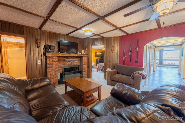 living room featuring coffered ceiling, a fireplace, and ceiling fan