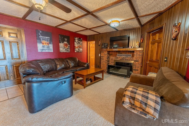 carpeted living room with coffered ceiling, a brick fireplace, wooden walls, and ceiling fan