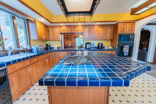 kitchen featuring tile countertops, a center island, and sink