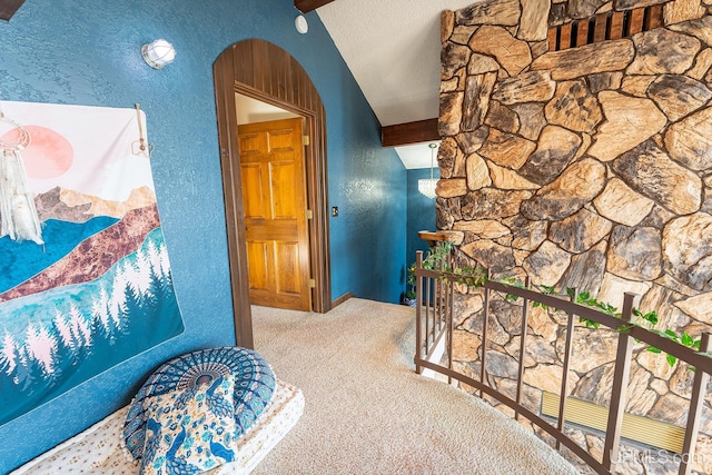 corridor featuring vaulted ceiling with beams, carpet floors, and a textured ceiling