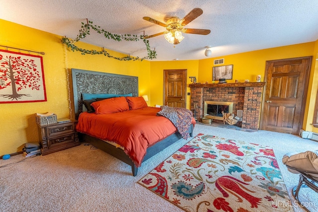 bedroom with ceiling fan, carpet flooring, a textured ceiling, and a fireplace