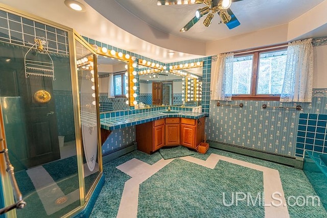 bathroom featuring a shower with door, tile walls, a baseboard heating unit, vanity, and tile patterned floors