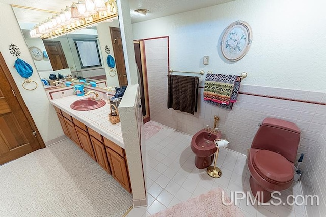 bathroom featuring tile patterned floors, toilet, tile walls, a bidet, and vanity