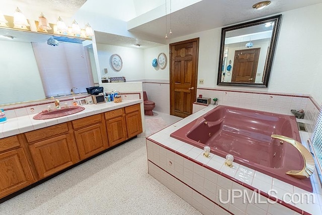 bathroom featuring toilet, vanity, and tiled bath