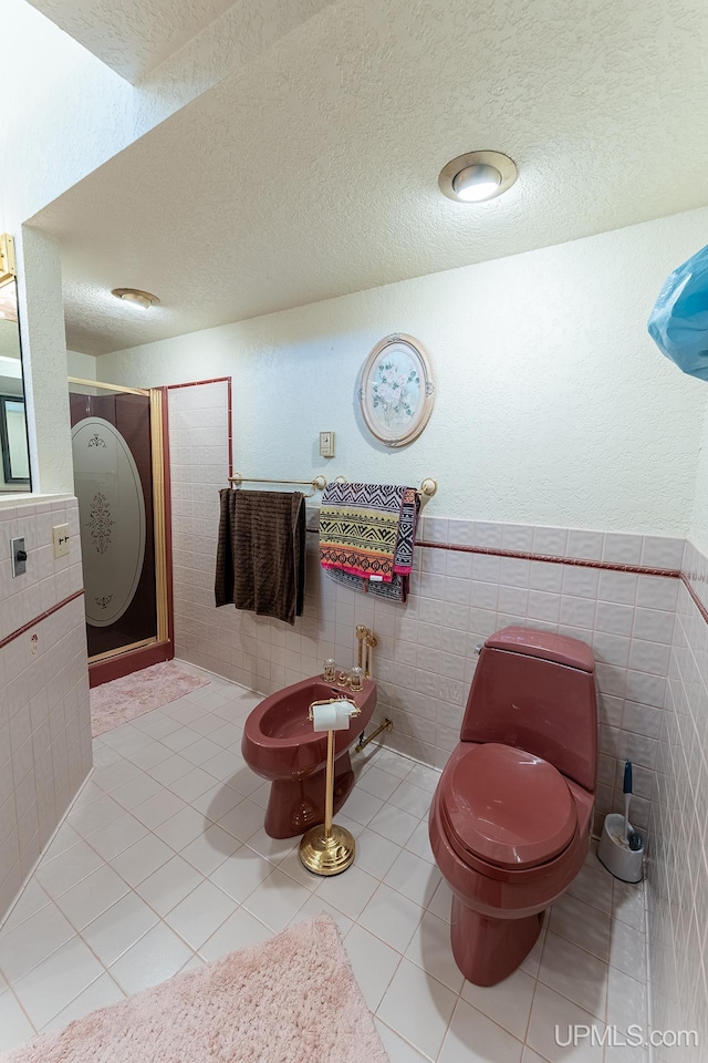 bathroom featuring a bidet, toilet, tile patterned flooring, and tile walls